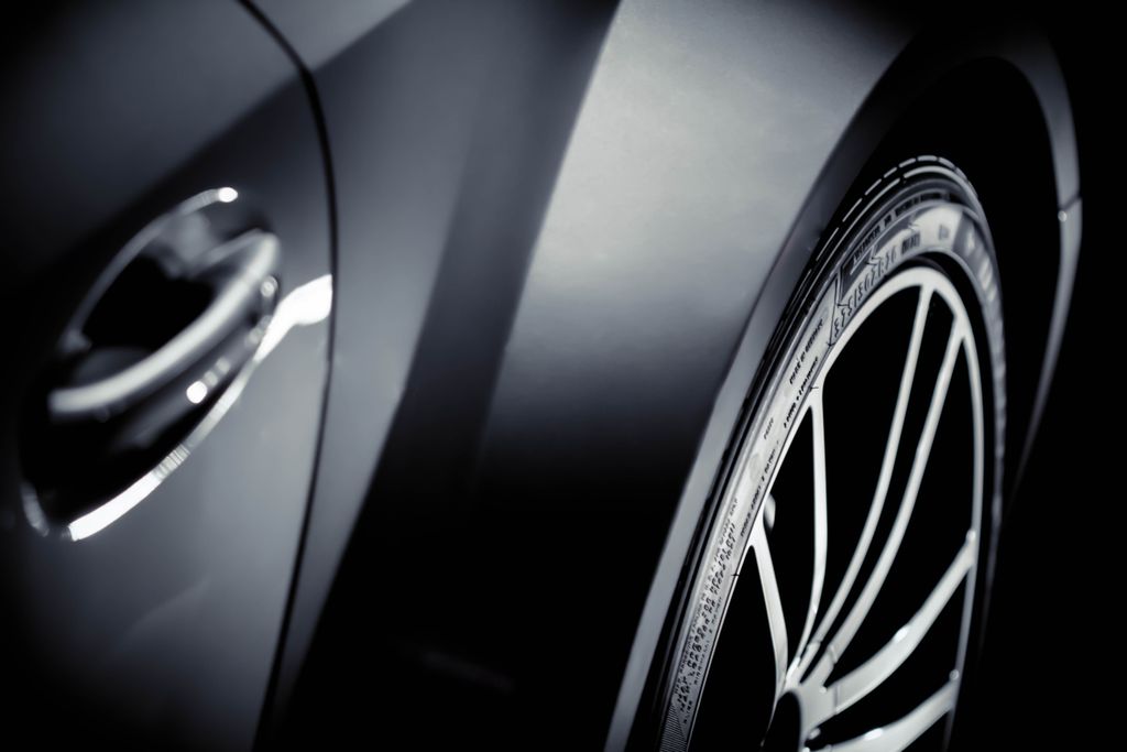 Close-up of a shiny gray car showcasing its chrome details and tire rim.